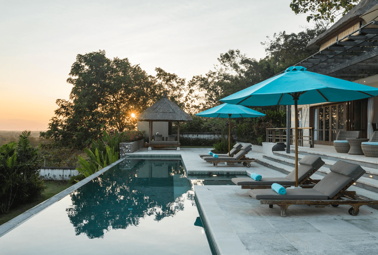 Modern pool renovation with sun loungers and turquoise umbrellas near Austin, TX